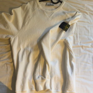 Vit långärmad tröja från Stone Island - Säljer en stilren vit långärmad tröja från Stone Island. Tröjan har en klassisk design med rund hals och den ikoniska logotypen på ärmen. Perfekt för en avslappnad och trendig look. Köpt för 3999 på miinto. Äkthetscertifikat FINNS! Pris går att diskutera. 