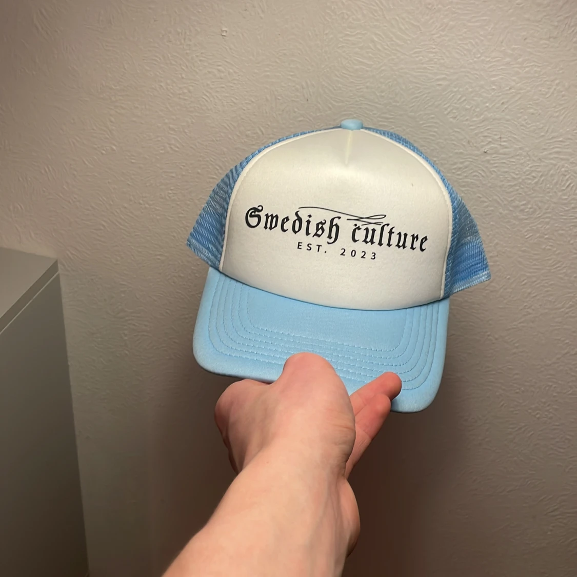 Ljusblå och vit keps med text