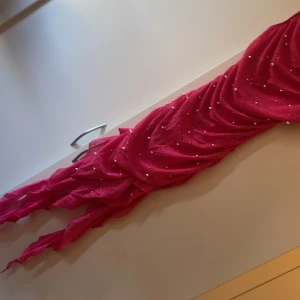 Rosa klänning med pärlor - Säljer en elegant rosa klänning med pärldetaljer. Klänningen har smala axelband och en draperad design som ger en fin siluett. Perfekt för speciella tillfällen.   Använd vid ett tillfälle.