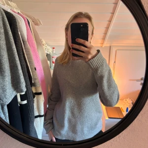 Grå stickad tröja från Vero Moda - Säljer en mysig grå stickad tröja från Vero Moda. Tröjan har en klassisk rund hals och långa ärmar, perfekt för kyligare dagar. Den är enkel att matcha med olika outfits och ger en stilren look.💞