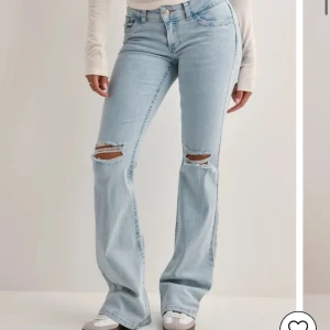 Eftertraktade ljusblå bootcut jeans från Nelly  - Snygga ljusblå bootcut jeans med slitningar på knäna och broderade detaljer på bakfickorna. Perfekta för en avslappnad stil med en touch av edge. OBS❗️endast använda ett fåtal gånger 