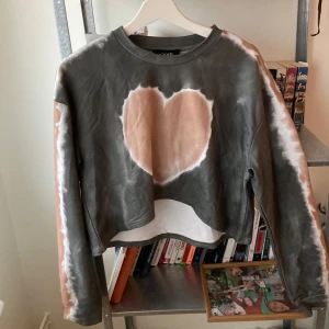 Tiedye tröja från Cider - Croppad collegetröja med tiedye motiv av ett hjärta på framsidan i grågrönt och rosa. Knappt använd! 