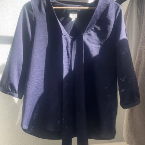Mörkblå satin blus med knytband - Säljer en elegant mörkblå satin blus med trekvartsärmar och  knytband framtill. Använd ett få tal gånger säljer för att den är för liten kom privat för fler bilder❣️