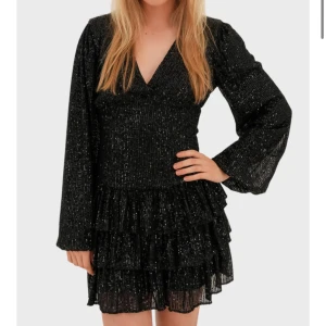 Svart ”Paris” klänning - Svart glittrig ”Paris” klänning med v-ringning och långa ärmar i storleken S/M från Meet Me There. Köpte i misstag fel storlek så den är i perfekt skick!