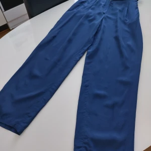 Blå sidenbyxor från Betty Barclay - Snygga blå byxor i 100% siden från Betty Barclay. De har en elegant och luftig design med en rak passform som ger en stilren look. Perfekta för att ge en touch av lyx till din garderob.