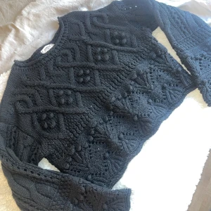 Svart stickad tröja - Säljer en svart stickad tröja med ett unikt mönster. Tröjan har långa ärmar och en croppad passform som ger en trendig look. Endast använd en gång. Köpt på chiquelle i str M/L. Nypris 599kr