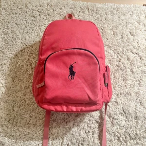 Rosa ryggsäck från Ralph Lauren🌸 - Säljer denna rosa ryggsäck från Ralph Lauren då den inte kommer till användning. Mycket bra skick (har dock ett pyttelitet rivmärke på framsidan). Denna modell säljs inte länge men motsvarande modell kostar runt 800 i nypris. Pris kan diskuteras.