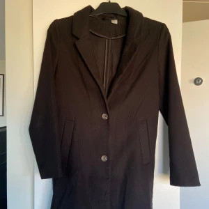 Svart kappa - Tunn svart kappa med klassisk design och knappar framtill. Den har en stilren krage och långa ärmar. Passar till vår och sommar, inte tillräckligt varm för vintern! Sparsamt använd då den är för liten för mig. 