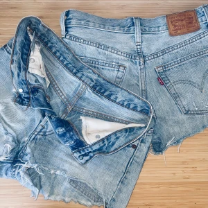 Blå jeansshorts från Levi's - Säljer två par coola blå jeansshorts från Levi's med fransiga kanter och slitna detaljer. (Hitta det andra paret på min profil) Perfekta för en avslappnad stil. De har klassiska fem fickor och knappgylf. Passar perfekt för sommardagar! 