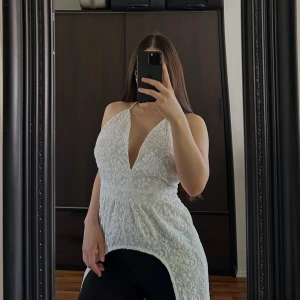 Topp - Elegant vit klänning från Bik Bok i spets med djup v-ringning och öppen rygg. Klänningen är ärmlös och har en lång design som ger en sofistikerad look. Perfekt för speciella tillfällen.🥰🥰🥰