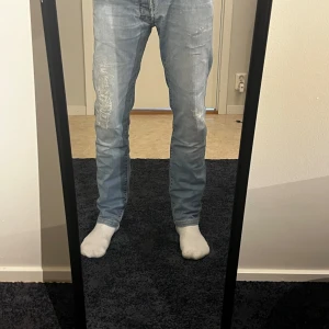 Ljusblå jeans från Jacob Cohen - Snygga ljusblå jeans från Jacob Cohen med en klassisk femficksdesign och subtila slitningar för en trendig look. Jeansen har en knappgylf och broderad detalj på myntfickan. Perfekta för en avslappnad stil. Det finns farbrors slitningar och även broderade detaljer som gör plagget unikt. Det är storlek 34/33 och passar även bra för personer med mindre storlek i midjan. Kom gärna med frågor och prisförslag!😃