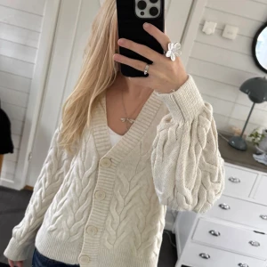 Vit stickad kofta med flätmönster💓 - Säljer en mysig vit stickad kofta med ett snyggt flätmönster. Koftan har långa ärmar och knappar framtill. Perfekt för kyliga dagar och ger en stilren look. Passar bra till jeans eller kjol.