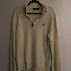 Beige tröja från Ralph Lauren - Säljer en stilren beige tröja från Ralph Lauren med dragkedja och broderad logga på bröstet.  Har en söitning på armen.