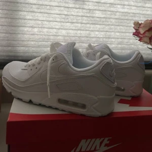 Vita Nike Air Max 90 -  stilrena vita Nike Air Max sneakers. Skorna har en klassisk design med synlig luftdämpning i sulan och snörning framtill. Perfekta för både vardag och träning. Strl 43