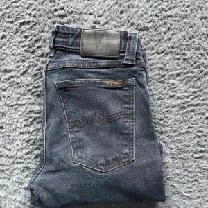 Nudie Jeans - Snygga svarta jeans från Nudie Jeans med en tight passform. De har en klassisk femficksdesign och är tillverkade i ett stretchigt material för extra komfort. Perfekta för en stilren look.