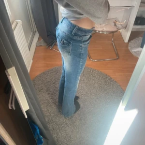 Blåa bootcut jeans med broderade fickor - Blåa bootcut jeans i bra skick bara lite slitna där nere. Det är storlek xs och dom är stretchiga. Några stenar har ramlat av på bakfickorna men det är inget som tydligt syns.