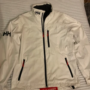 Helly Hansen jacka - Säljer en stilren vit vindjacka från Helly Hansen. 8/10 skick. Passar dig som är runt 180-190