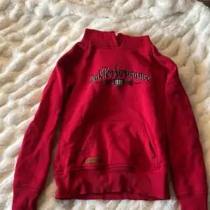 Säljer en snygg röd hoodie från Peak Performance med broderad logga på framsidan. Tröjan har en praktisk magficka och ribbade muddar vid ärmslut och nederkant. Perfekt för kyliga dagar!