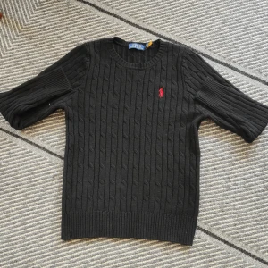 Svart kabelstickad polo ralph lauren tröja. Du får gärna ge prisförslag. - En svart kabelstickad tröja från polo ralph lauren. Nästan nytt skick. Tröjan är svart och har en röd logga. 