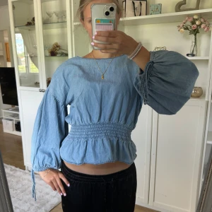 Blå blus med puffärm från Bik Bok - Supersöt ljusblå blus från Bik Bok i storlek S. Blusen har bred resår i midjan, volangkant och puffiga långärmar med knyt vid ärmslutet. Materialet är mjukt och känns som bomull.