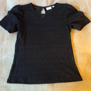 Svart spetsblus från Vila, M - Svart blus från Vila i storlek M, med korta ärmar och genombruten spets med snyggt mönster. Endast använd ett fåtal gånger💗