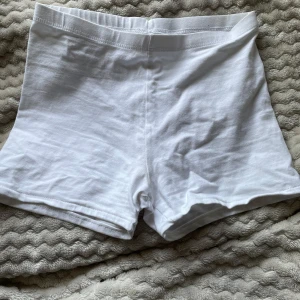 Vita basic cykelbyxor från lager 157 - Vita, enkla shorts från lager 157 i mjuk bomull med lite stretch. Modellen är mid/highwaist och har en clean look utan detaljer eller fickor. Perfekta till sommaren när du vill ha något under kjol.