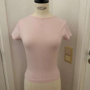 Ljusrosa topp xs - Ljus puderrosa  topp med korta ärmar och rund hals. Supermjuk & slim passform som sitter snyggt mot kroppen. XS.  Perfekt för dig som gillar enkel och clean stil. Kan hämtas på Hägerstensåsen 🌸