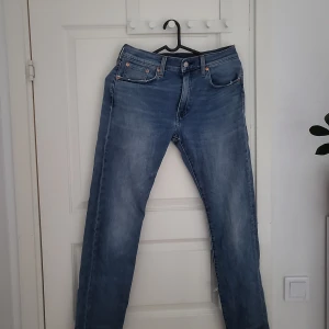 Levi's 502 blå jeans W30 L32 - Säljer ett par klassiska Levi's 502 jeans i ljusblå tvätt. Modellen har raka ben, fem fickor och snygga kontrastsömmar. Jeansen är tillverkade i bomull och har en ikonisk läderpatch bak i midjan. Perfekta för en avslappnad och stilren look. Säljer då jag köpte fel storlek, heltny ca 1000-1200
