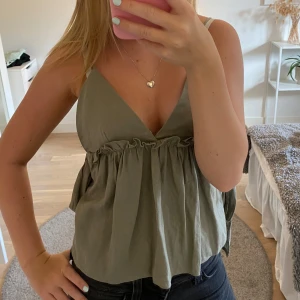 Topp - Jättefin mörkgrön topp. Den är knappt använd och i jättebra skick. Storlek XS men den har justerbara axelband och knyte i både sidorna vilket gör att man kan justera den mycket!! Såå fin