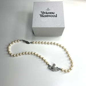 Vivienne Westwood pärlhalsband - Ikoniskt pärlhalsband från Vivienne Westwood med vita pärlor och ett silverfärgat orb-hänge med glittriga detaljer, alla stenar sitter kvar. Skickas i originalförpackning. Nypris 2300kr, skicka prisförslag 💕💕(mini bas relief pearl necklace)