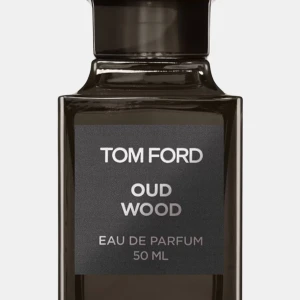 Tom Ford Oud Wood 50 ml parfym - Tom Ford Oud Wood Eau de Parfum i en elegant mörkbrun glasflaska på 50 ml med ca 40 ml kvar. Doften är lyxig och träig med inslag av oud, perfekt för dig som gillar exklusiva och unika parfymer. Flaskan har en stilren, fyrkantig design med svart etikett. 