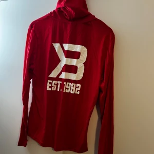 Röd gym-hoodie från Better Bodies - En röd hoodie från Better Bodies i storlek M. Tröjan har lång ärm, huva. Materialet är mjukt och känns som bomull, perfekt för chill eller träning.
