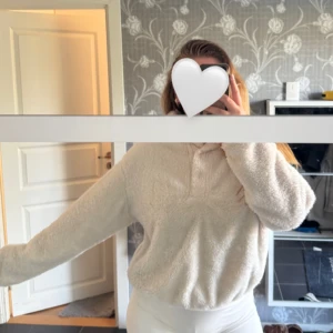 Vit fluffig fleece med knappar upptill - Supermysig vit fluffig fleece med långa ärmar. Perfekt för chill dagar och när du vill vara extra bekväm. Tröjan har en loose passform och känns riktigt mjuk mot huden. Snygg att matcha med leggings eller jeans.