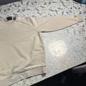 Beige sweatshirt från Lyle & Scott - Säljer en beige sweatshirt från Lyle & Scott med broderad logga på bröstet och den klassiska gula örnen på ärmen. Tröjan har rund hals, ribbade muddar och är tillverkad i mjuk bomull. Haft denna i ungefär 9 månader men bara använt 3 gånger