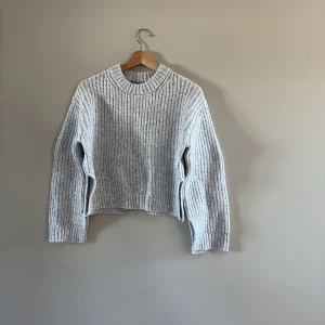 Ljusgrå stickad tröja Gina Tricot - Supermysig ljusgrå stickad tröja från Gina Tricot i storlek XXS. Tröjan har grov ribbstickning, rund hals och långa ärmar. Croppad passform med små slitsar i sidorna. 