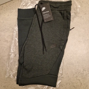 Oanvända Nike Tech Fleece byxor (S)  - Helt nya med lappen kvar. Mörkgröna. Ord.pris 1299 kr. Storlek S. I premium fleece vilket gör dem perfekta till höst/vinter eller kyligare dagar. Bild 3 och 4 är referens för formen. Skickas spårbart och försäkrat 