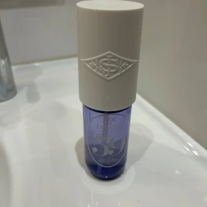 Sol de Janeiro 59 Parfymmist 90ml - Parfymmist från Sol de Janeiro, doft 59, i en snygg lila transparent plastflaska med vit cylinderformad kork. Doften har inslag av vaniljorkidé, sockrad viol och sandelträ. Flaskan rymmer 90 ml och har en modern, stilren design.