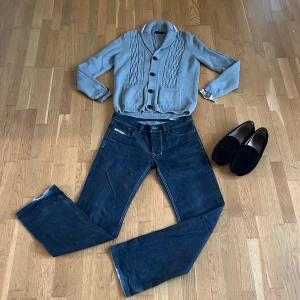 Sällsynta Vintage Diesel jeans Regular straight  - Säljer ett par mörkblå Diesel Larkee jeans med raka ben och klassiska kontrastsömmar. Det är en äldre modell som är väldigt sällsynta och inte tillverkas längre och jeansen är i en rå marinblå färg vilket är perfekt om du vill göra egna slitningar. Jeansen har fem fickor, tydliga bakfickor med V-detalj och en liten Diesel-logga vid linningen. Perfekta för dig som gillar en tidlös och avslappnad look. 