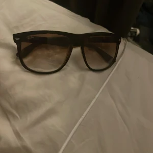 Ray-Ban bruna Wayfarer solglasögon - Snygga Ray-Ban Wayfarer solglasögon med brunmelerad båge och mörktonade glas. Klassisk och tidlös modell som ger en cool vibe till din stil. Perfekta för soliga dagar och passar till det mesta.