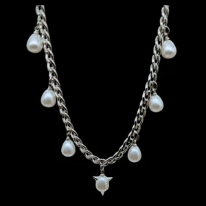 Chunky halsband med pärldroppar - Stilrent halsband i silverfärgad metall med sju hängande droppformade pärlor, varav en har coola stjärndetaljer. Kedjan är chunky och ger ett edgy intryck, perfekt för att lyfta vilken outfit som helst. Pärlorna är vita och ger en snygg kontrast mot den silvriga kedjan.
