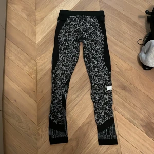 Adidas Stella McCartney leggings XS - Snygga svarta och grå leggings från Adidas Stella McCartney i storlek XS. De har blommigt mönster och coola meshdetaljer, perfekt för träning. Materialet är stretchigt och följsamt för maximal komfort.