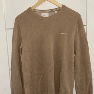 Beige stickad tröja från GANT - Säljer en snygg beige brun stickad tröja från GANT med logga på bröstet. Tröjan är använd vid 2 tillfällen då jag inte riktigt tyckte den passade mig i utseende. Tröjan är i storlek herr S, men passar för M. Pris diskuteras vid intresse då tröjan knappt är använd!