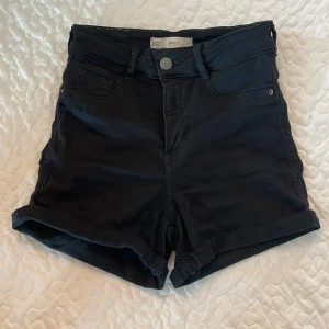 Svarta högmidjade shorts Molly XS - Svarta shorts från Molly, g perfect jeans, i storlek XS. Högmidjade med klassisk femficksdesign, uppvikta benslut och knappstängning framtill. Materialet är mjukt och stretchigt, perfekt för chill dagar. Snygg och enkel look som funkar till allt.