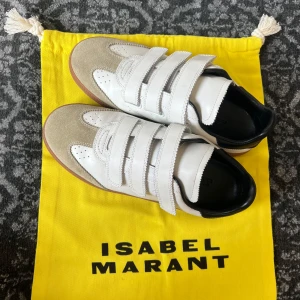 Vita sneakers Isabel Marant med kardborre - Snygga vita sneakers från Isabel Marant med beige mockadetaljer, svart häl och brun sula. Säljer då det är lite små för mig.💕nypris 4400kr