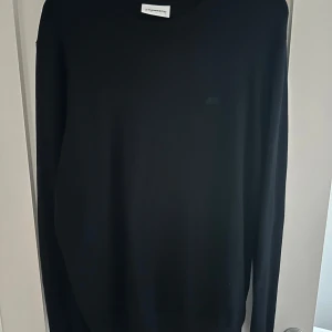 Marinblå stickad tröja från Lindbergh - Marinblå stickad tröja från Lindbergh i storlek Large med rund hals och diskret logga på bröstet. !!!!!    Nypris 699kr !!!! Tröjan är perfekt för att ha utanpå skjortor. Perfekt för dig som gillar stilrena och enkla plagg med snygg passform.