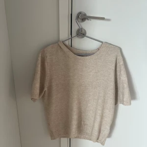 Beige stickad kortärmad tröja - Skön stickad T-shirt från hm i storlek M. Säljer då den inte kommer till användning och den är i bra skick. 