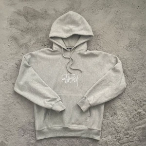 Grå Stüssy hoodie  - Säljer min grå Stüssy hoodie i storlek M, oversized passform. Sjukt skön och sitter fett nice, perfekt till streetwear/staple outfits. Använd ett fåtal gånger, inga fläckar                   100% bomull Passar både killar & tjejer.  ✅ Fint skick ✅ Oversized fit ✅ Stüssy logga framtill  📏 Size: M 🎨 Färg: Grå 🔖 Märke: Stüssy 📦 Frakt: Samma/Nästa dag   💬 DM ifall de finns frågor! 