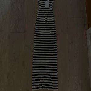 Randig ribbad långklänning Bershka - Snygg långklänning från Bershka i svart och vitt med horisontella ränder. Klänningen är ribbad och har en kroppsnära passform som framhäver siluetten. Perfekt för dig som gillar en stilren och trendig look. Aldrig använd. Kan mötas på Ekerö annars skickar jag och köparen står för frakten.