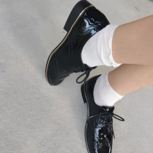 Svarta lackloafers från Anna Field - Snygga svarta loafers i glansigt lackmaterial från Anna Field. Skorna har klassisk snörning, låg klack och dekorativa broguedetaljer. 