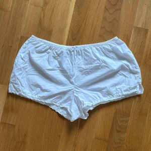 Vita shorts med spetsdetaljer, Bikbok - Säljer ett par jätte söta vita shorts från Bikbok i storlek S. De har elastisk midja, söt rosett framtill, liten slits på sidorna vid benen och spetsdetaljer längs bensluten. (Aldrig använda). 